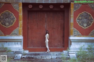 A naked woman sitting on top of a window sill.