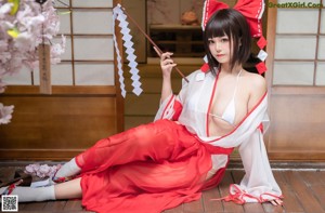 A woman in a red and white dress sitting on a bench.