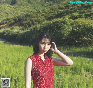 A woman in a red dress is walking through a field.