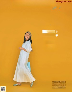 A woman in a white shirt and beige pants posing for a magazine.