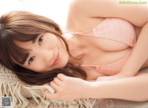A woman in a pink bikini leaning against a wall.