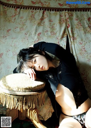 A woman in a blue sweater is sitting on a chair.