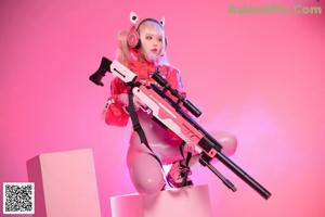 A woman in a pink outfit holding a pink gun.