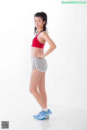 A woman in a red sports bra top and gray shorts.