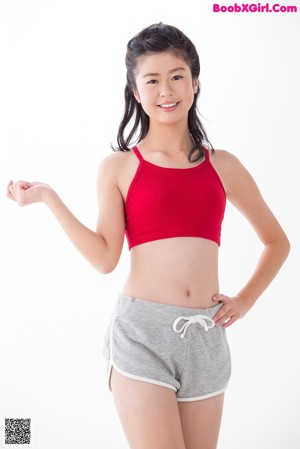 A woman in a red top and gray shorts posing for a picture.