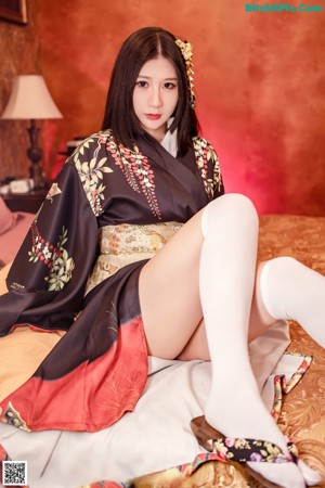 A woman sitting on top of a bed wearing white stockings.