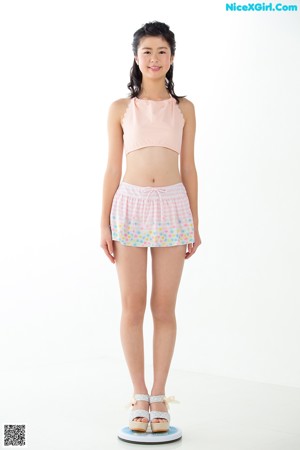 A woman standing on a scale in a pink top and shorts.