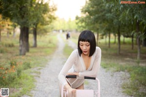 A woman in a white bodysuit leaning on a pink shopping cart.