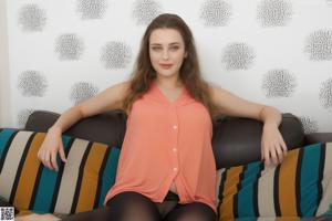 A woman in a white shirt is sitting on a bed.
