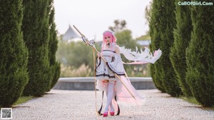 A woman with pink hair sitting on a chair holding a sword.