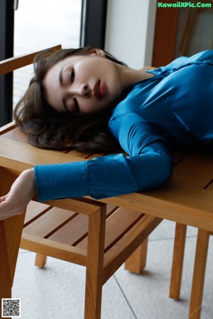 A woman in a blue dress laying on a couch.