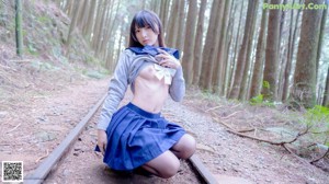 A woman in a school uniform is posing on a train track.