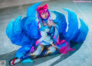A woman in a blue and pink outfit sitting on a bed.