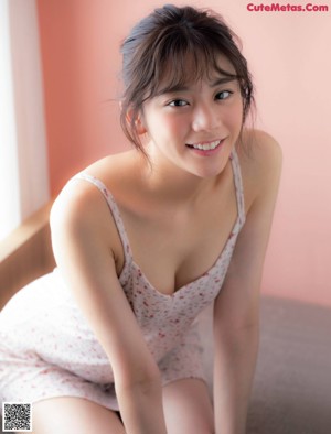 A woman sitting on top of a bed in a blue shirt.