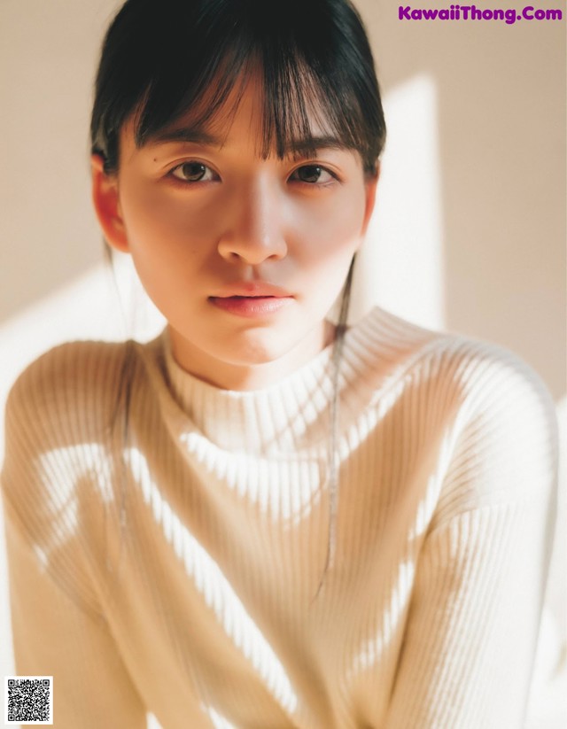 A woman in a white sweater is looking at the camera.