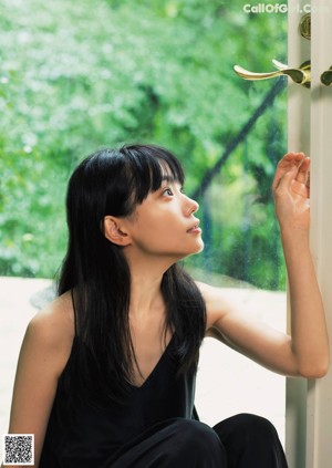A woman sitting on a couch with her hand on her chin.