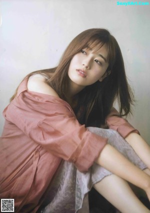 A woman with long brown hair and bangs is posing for a magazine.