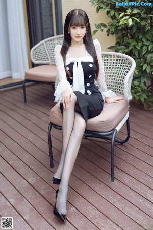 A woman in a black dress and white shirt posing for a picture.