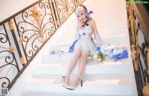 A woman sitting on a white chair holding a bouquet of flowers.