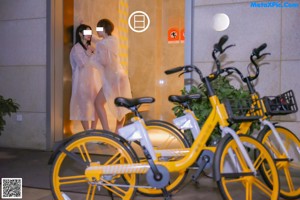 A couple of naked women riding on the back of a bike.