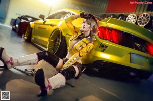 A woman in a yellow jacket and black gloves sitting next to a white car.