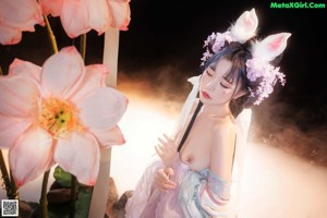 A woman in a pink and blue dress standing in front of flowers.