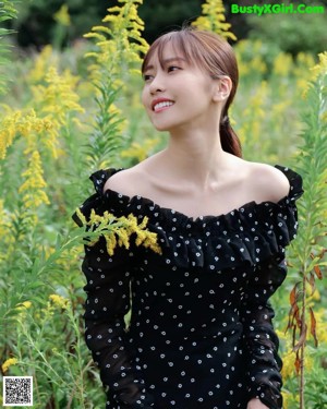 A woman in a black and white polka dot dress standing on a dirt road.