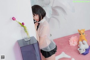 A woman sitting on a pink floor holding a stuffed animal.