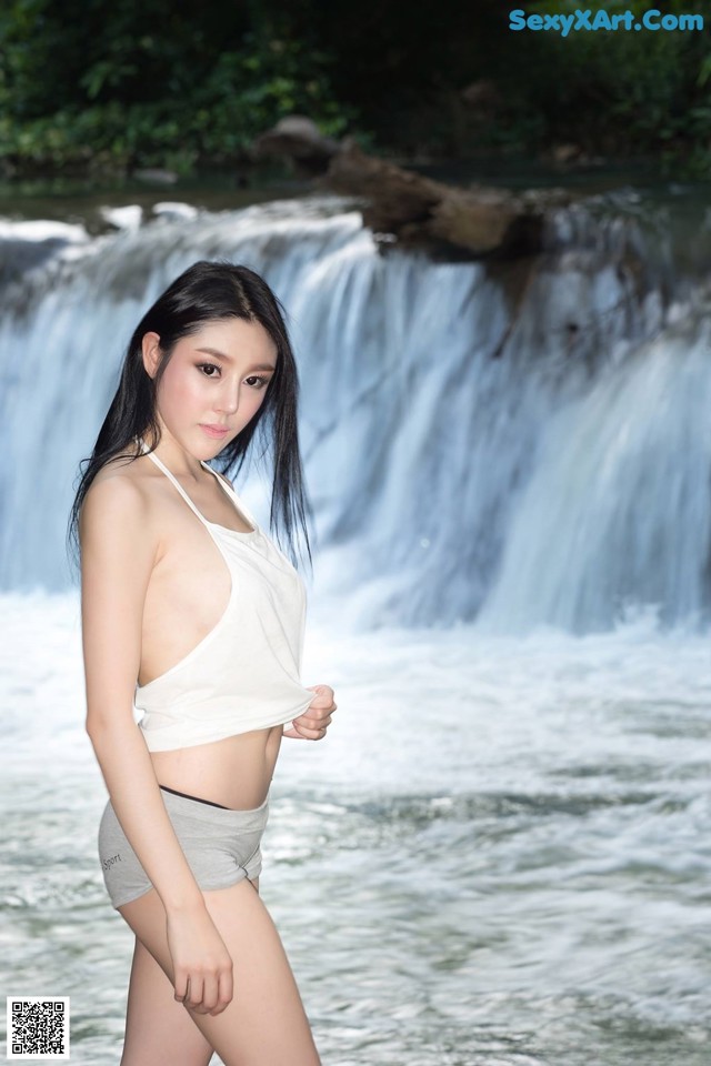 A woman standing in front of a waterfall.