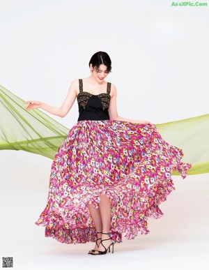A woman in a black top and a colorful skirt.