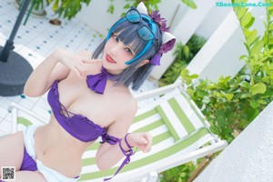 A woman in a purple bikini sitting on a green chair.