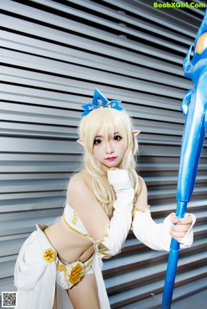 A woman dressed in a white and blue outfit holding a blue wand.