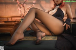 A woman sitting on a bed holding a fan.