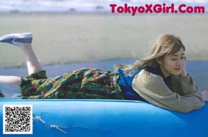 A young girl laying on top of a blue car.