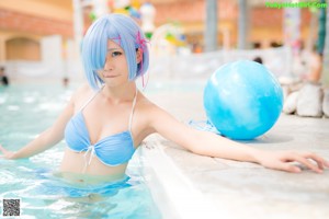 A woman in a blue bikini sitting next to a pool.